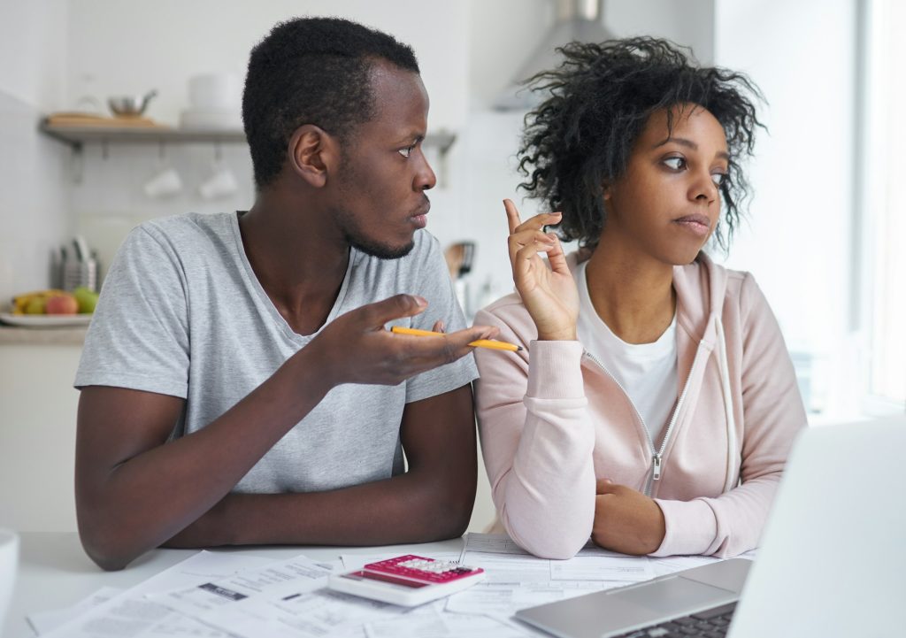 Angry family arguing about serious financial problems, sitting at kitchen table