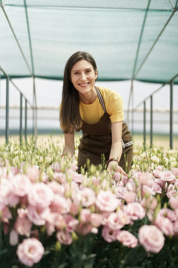 Pretty woman working with flowers in the green house